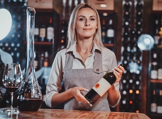 Uma sommelier bela e jovem segurando uma garrafa de vinho